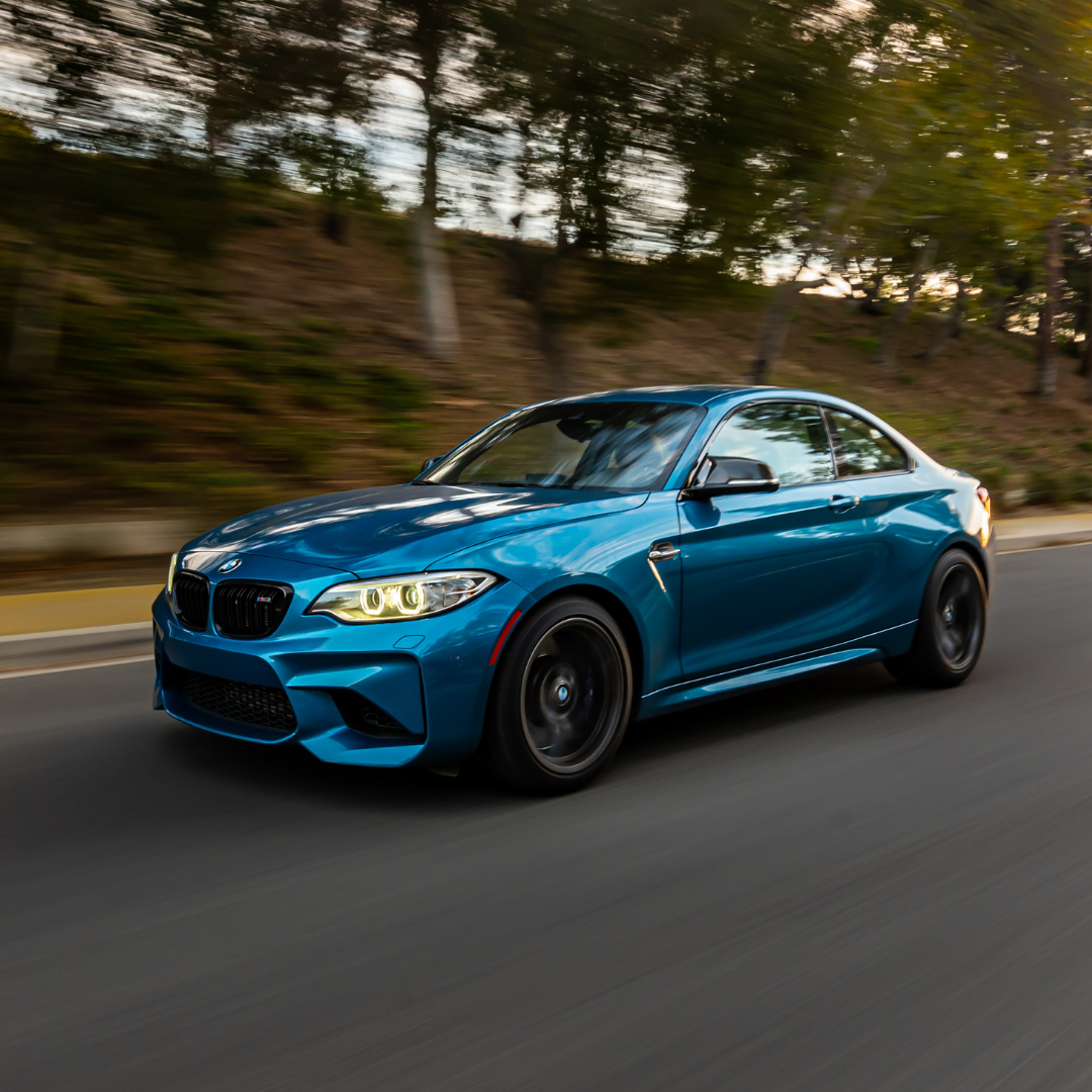 A blue BMW driving down the road collection speed and mileage information from Moving Intelligence tracker.